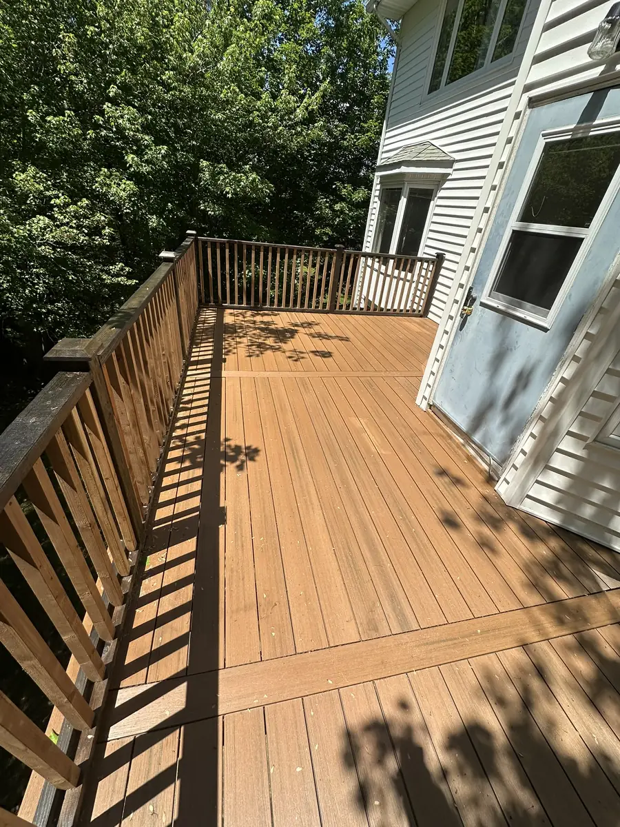 Finished deck with wood railings running along the back of a house