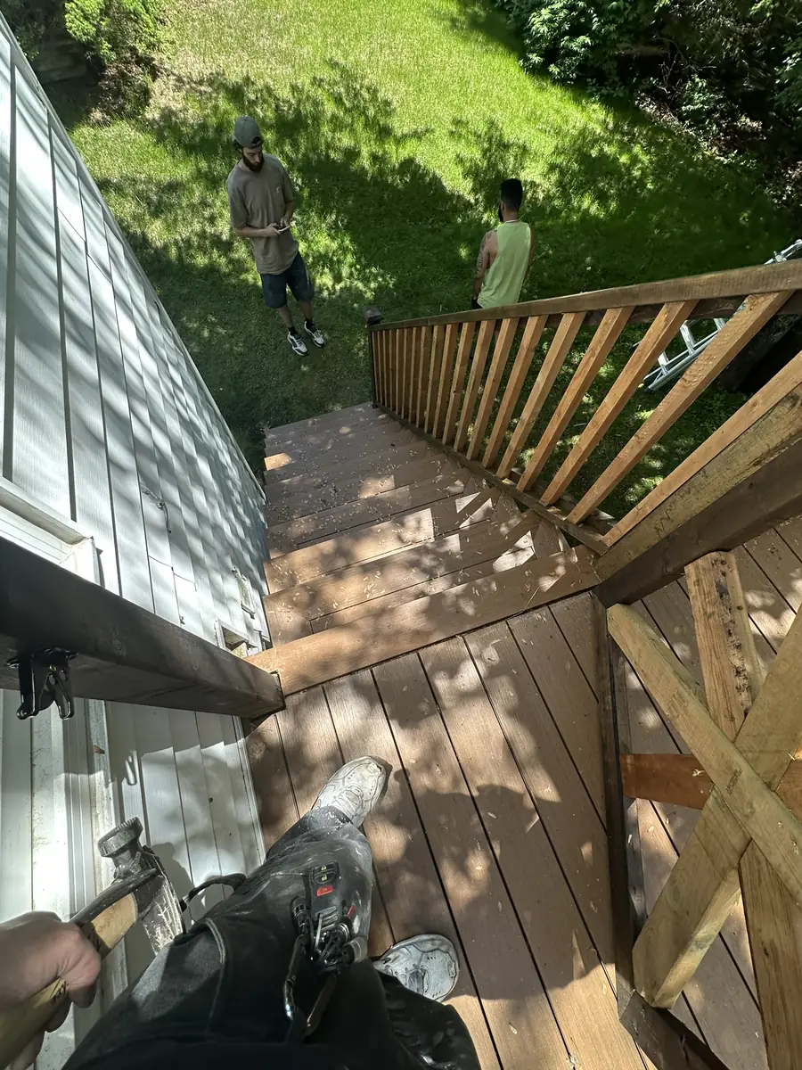 Deck rebuild in progress - stair treads lifted and new railing sections framed, crew on site
