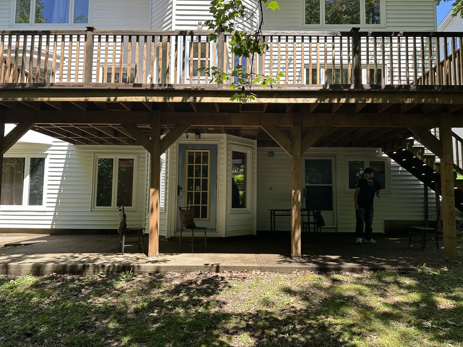 Fresh rebuilt elevated deck underside on a white-sided house after structure replacement