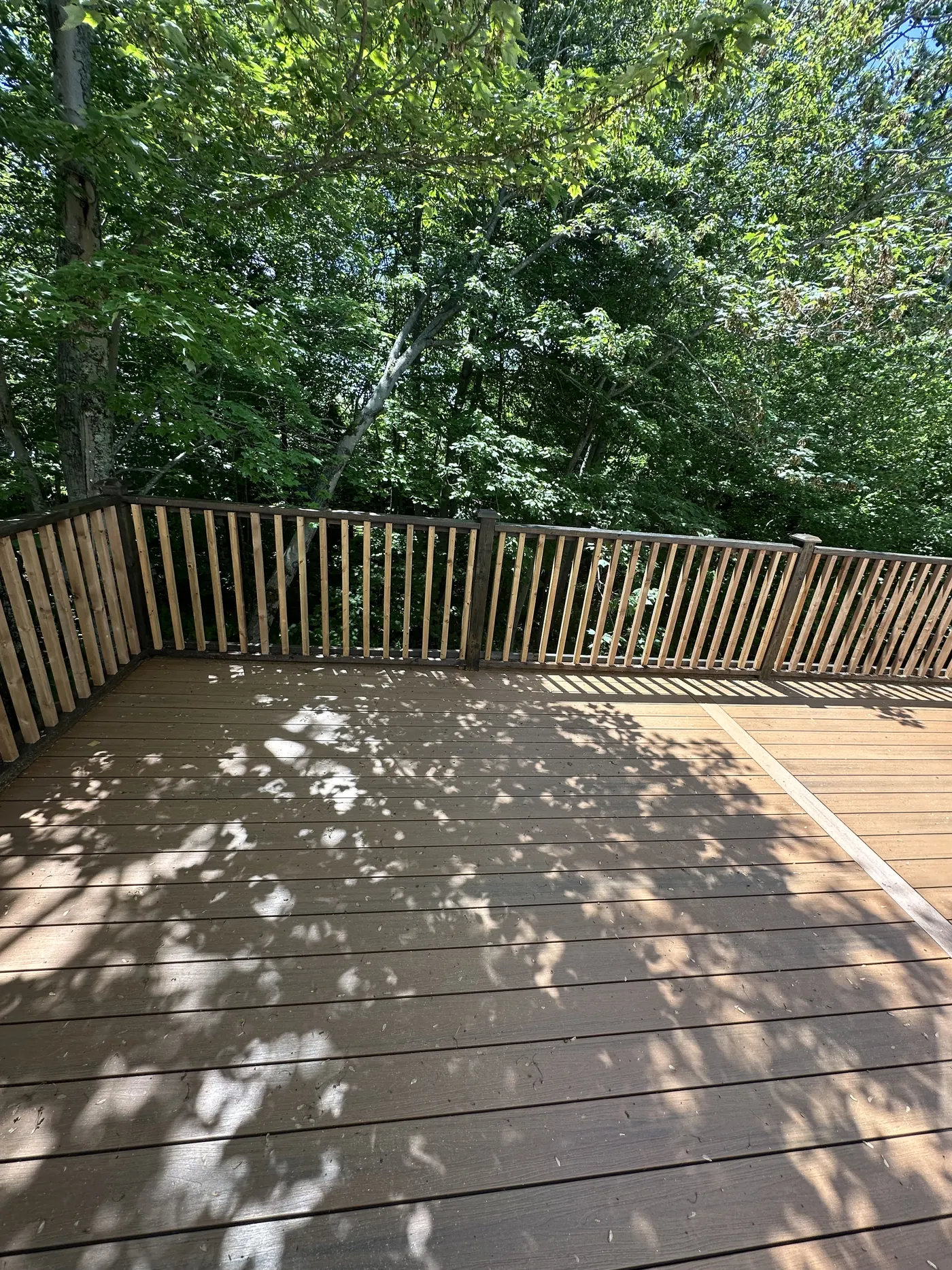 Finished deck with new wood railings backing onto woodland