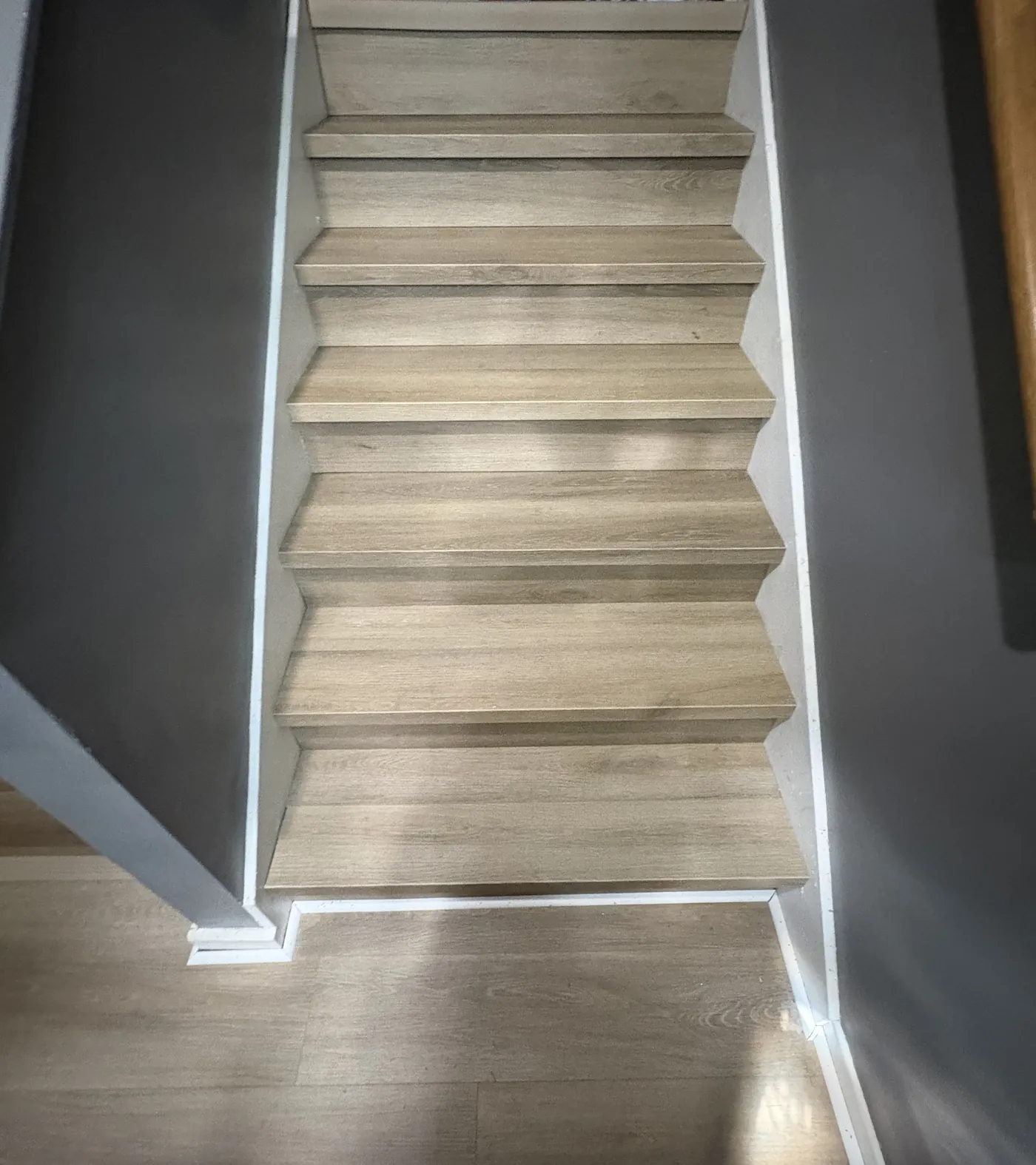 Finished light wood-look vinyl stair treads and risers against charcoal walls