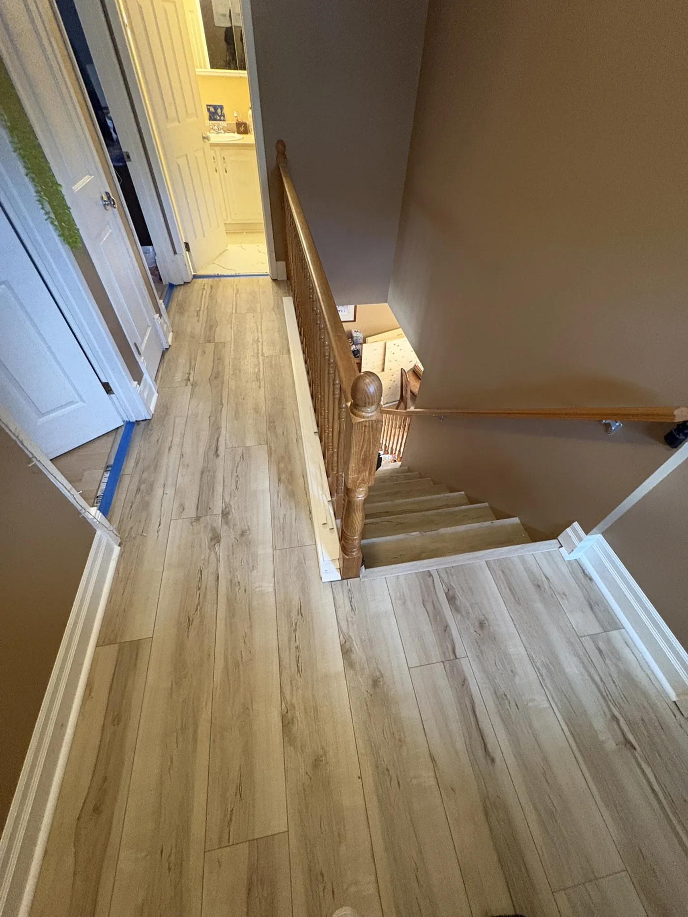 Light wood-look vinyl plank flooring mid-install with cutting tools and material staged